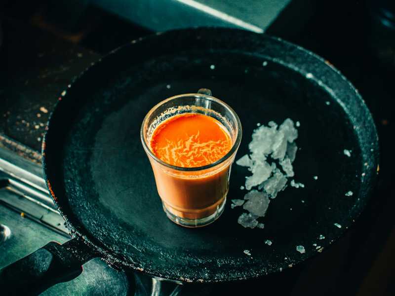 Karak masala chai in a glass cup with sugar cubes.