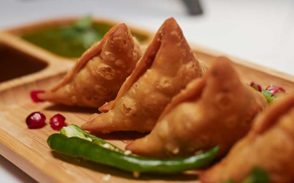 Crispy fried samosas served on a plate.